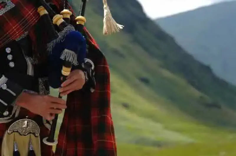Bagpiper playing in the Scottish Highlands