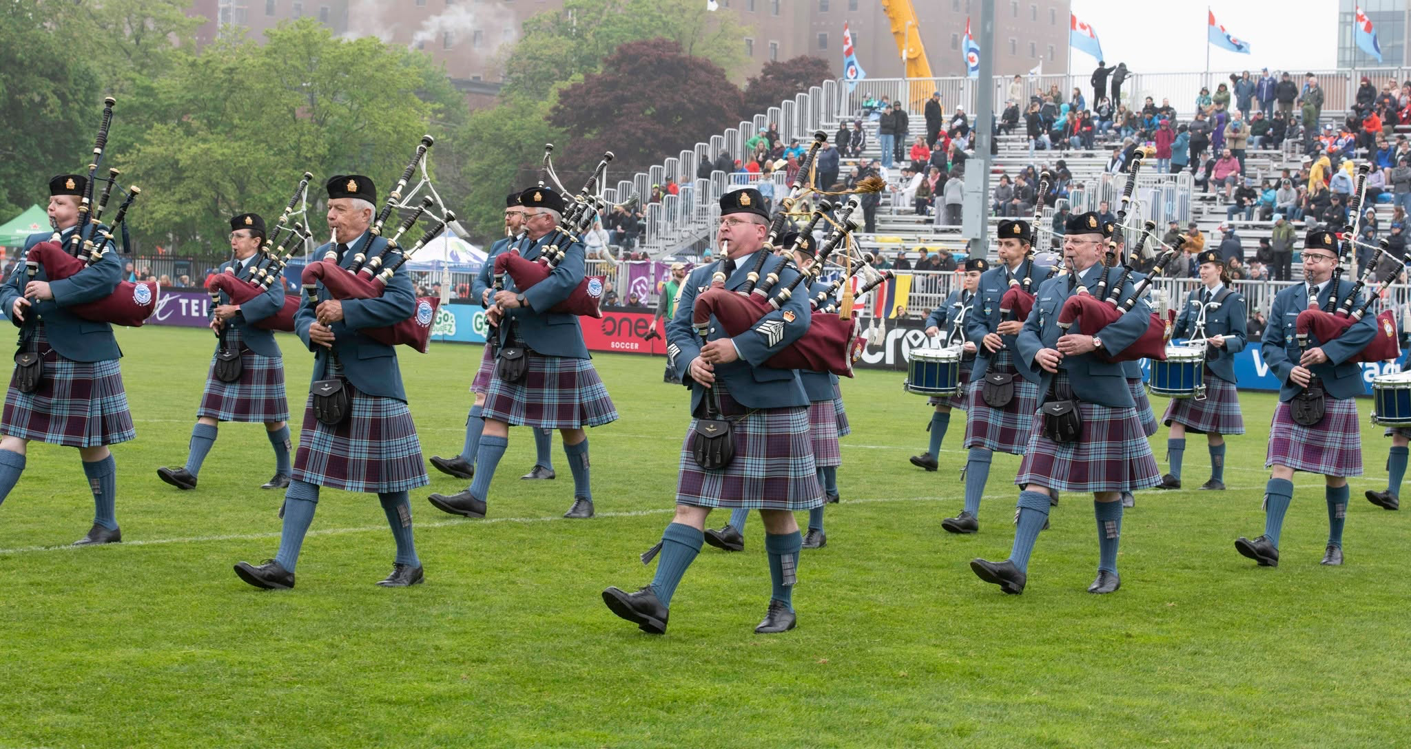 12 Wing Pipes and Drums marching on a playing field